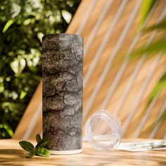 a vase sitting on top of a wooden table next to a glass cup and plant