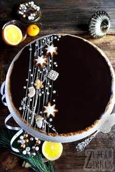 a chocolate tart decorated with stars and icing on a wooden table next to oranges