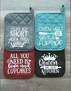 three oven mitts with words on them sitting on top of a wooden table next to each other