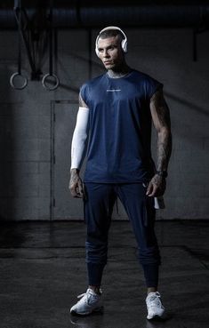 a man with headphones on standing in a dark room wearing blue and white clothing