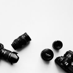 three cameras sitting next to each other on top of a white surface with lens caps