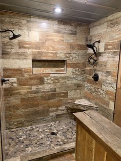 a walk in shower sitting next to a wooden bench and counter with lights on it