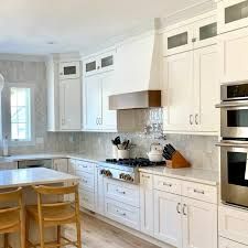 a kitchen with white cabinets and an island in front of the stove, oven, microwave and dining room table