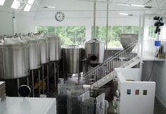 a room filled with lots of metal tanks next to a white counter top and stairs