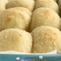 several rolls in a blue dish on a table with white polka dot napkins around them