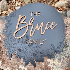 the bruce family sign sits on top of a rock in front of leaves and flowers