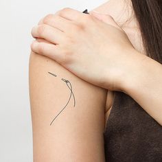 a woman's arm with a small flower tattoo on the left side of her arm