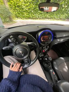 a person sitting in the driver's seat of a car with their hands on the steering wheel