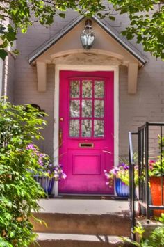 a bright pink door sits in front of a house