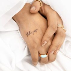 two hands holding each other with the word tattoo on their left side ribcage