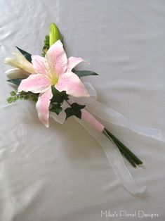 a pink and white flower bouquet sitting on top of a bed