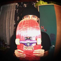 a man holding a skateboard in front of his face