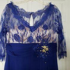 a blue dress with lace and flowers on the bottom, attached to a hanger