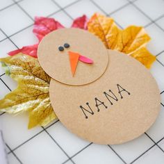 a paper turkey sitting on top of a table next to leaves and a marker that says mama