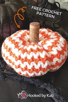 an orange and white knitted pumpkin sitting on top of a pile of black fabric