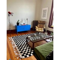 a living room filled with furniture and a checkered rug on top of a hard wood floor