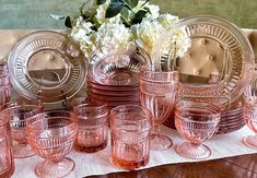 a table topped with lots of pink glasses and plates