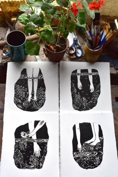 three black and white prints on top of a wooden table next to potted plants