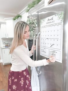 a woman is looking at a calendar on the refrigerator