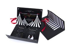 an open black and white box with red ribbon on the top, inside it is a circus tent