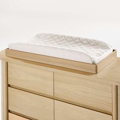 a wooden dresser with a mattress on it's top shelf and drawers in front of it