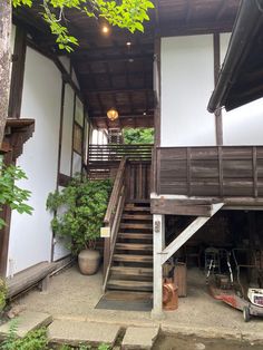 an old building with stairs leading up to the second floor and potted plants on the other side