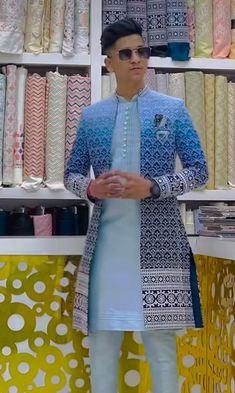 a man standing in front of a shelf filled with fabrics