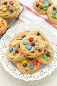 chocolate chip cookies with m & m candies on a white plate next to other cookies