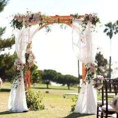 an outdoor wedding ceremony setup with white draping and pink flowers on the arch