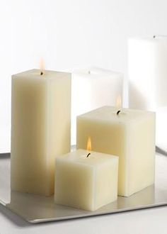 three white candles sitting on top of a metal tray