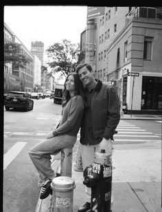 a man and woman standing next to a fire hydrant on the side of a street