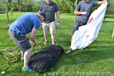 three men are working on an object in the grass with one man holding a flag