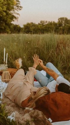 a man and woman laying on the ground with their hands in the air while holding each other