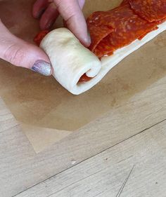 a person holding a piece of food in their hand on top of a wooden table