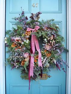 a blue door with a wreath and pink ribbon hanging on it's front door