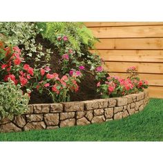 a garden with flowers and plants growing in the ground next to a wooden fenced wall