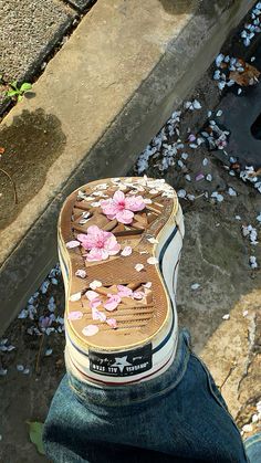 a person's shoes with pink flowers on them sitting in front of a puddle