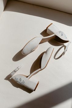 two pairs of shoes sitting on top of a white surface