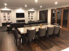 a large dining room table and chairs in front of a flat screen tv mounted on the wall