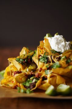 nachos with sour cream and chopped vegetables on a wooden plate, ready to be eaten