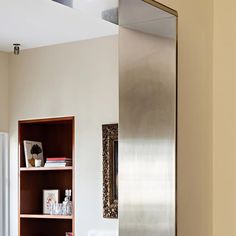 a stainless steel refrigerator sitting in the corner of a room next to a book shelf