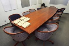 an empty conference room with several chairs and a wooden table in the center is covered by small boxes that are stacked on top of each other tables