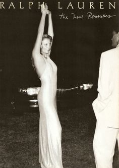 a black and white photo of a woman in a long dress holding her arm up