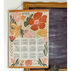 a calendar hanging on the wall next to a chalkboard with flowers painted on it