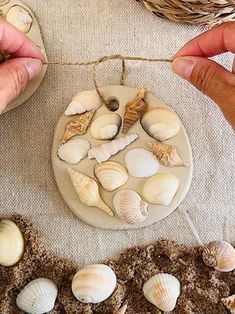 two hands are decorating seashells on a table