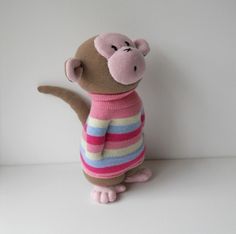 a stuffed animal is wearing a sweater and standing on its hind legs in front of a white wall