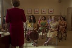 a group of women sitting around each other in front of a woman with a laptop