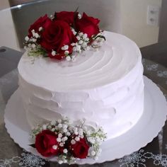 a white cake with red roses and baby's breath