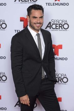 a man in a suit and tie standing on a red carpet