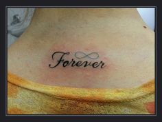 a woman's upper back tattoo with the word forever written in cursive font